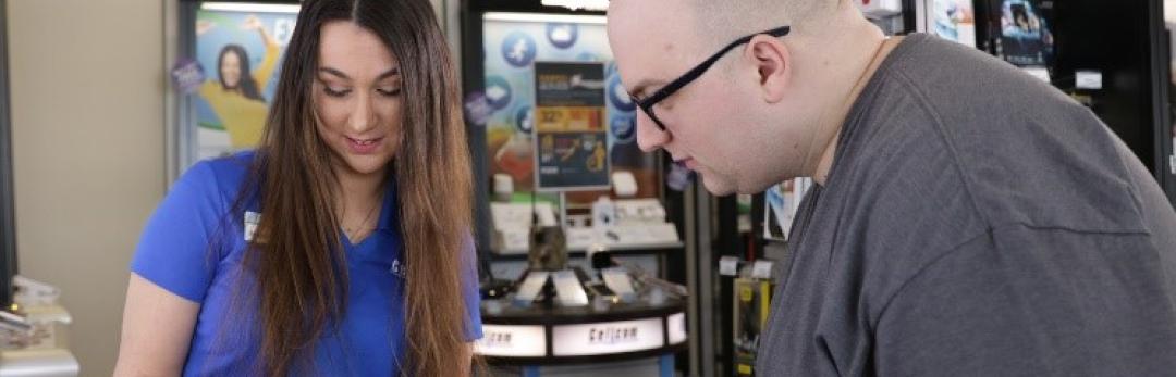 Cellcom employee showing a man a phone in store.