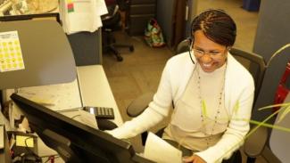 African american woman smiling while working at a computer with a headset on