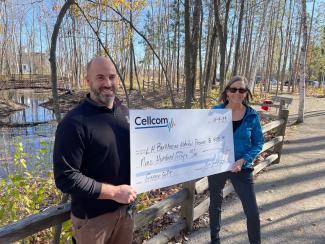 Two people holding a donation check for Cellcom's Green Gifts program.