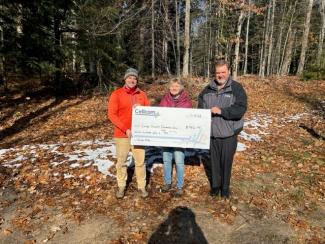 Three people holding a donation check for Cellcom's Green Gift