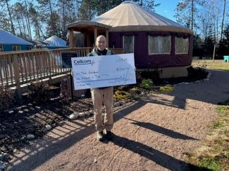 Person holding donation check for Cellcom's Green Gift program.