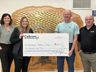 Group of four holding a donation check for Cellcom's Green gifts.