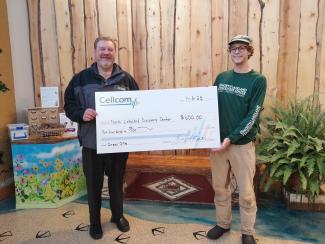 Two people holding a donation check for Cellcom's Green Gifts program.