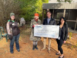 Group of four holding large donation check