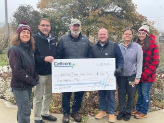 Group of six standing and holding a donation check for Cellcom's Green Gifts.