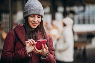 Woman in winter coat and winter hat holding a cell phone