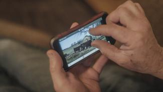 Man looking at camera live feed on phone, zooming in.