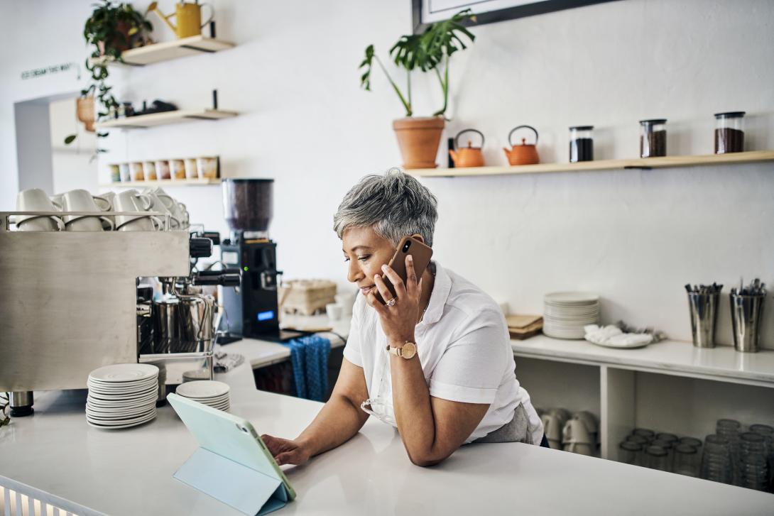 diner owner at counter on cell phone with tablet